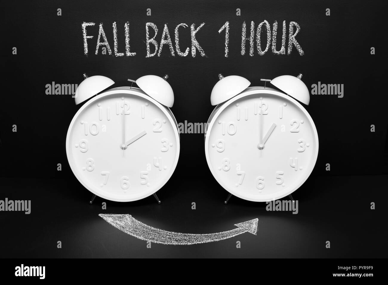 Fall back concept Autumn Time change. Two vintage clocks with chalky text on blackboard Stock Photo