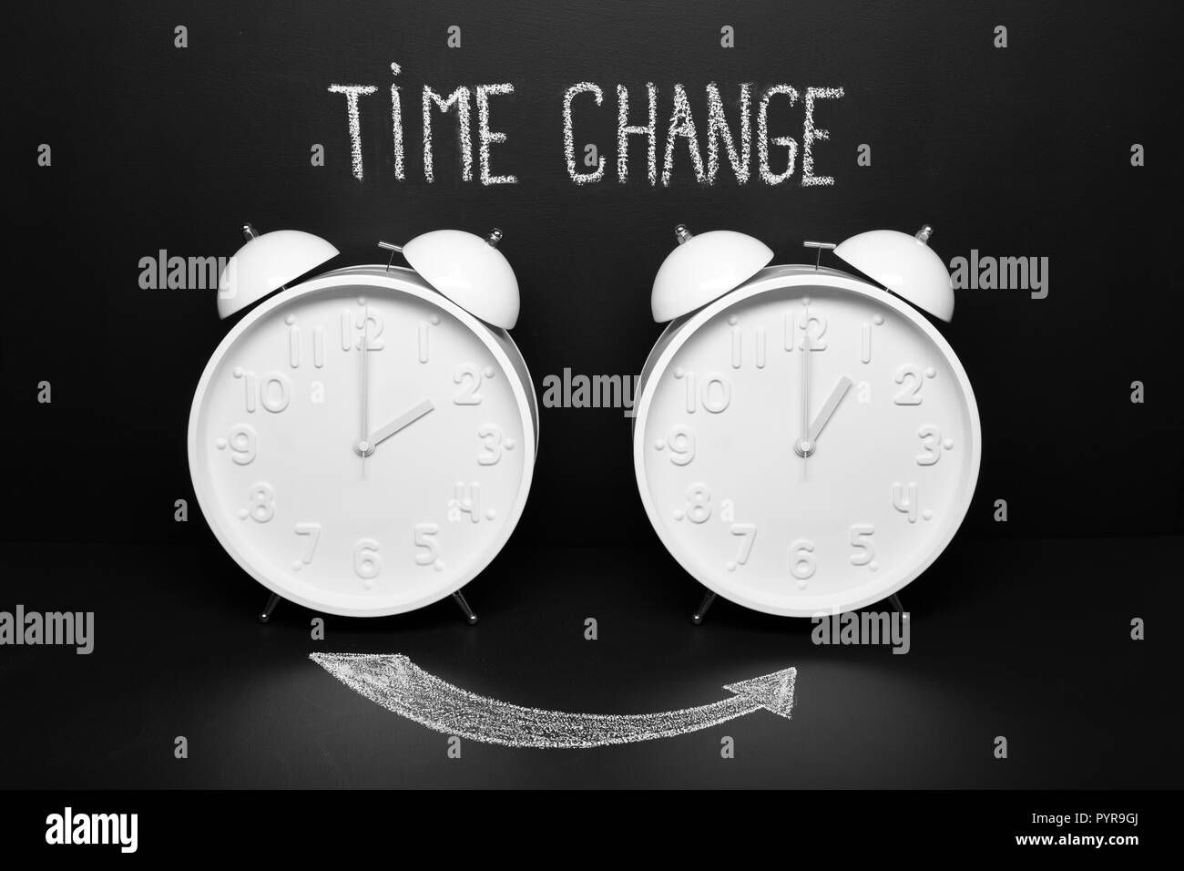 Autumn Time change Fall back concept . Two vintage clocks with chalky text on blackboard Stock Photo