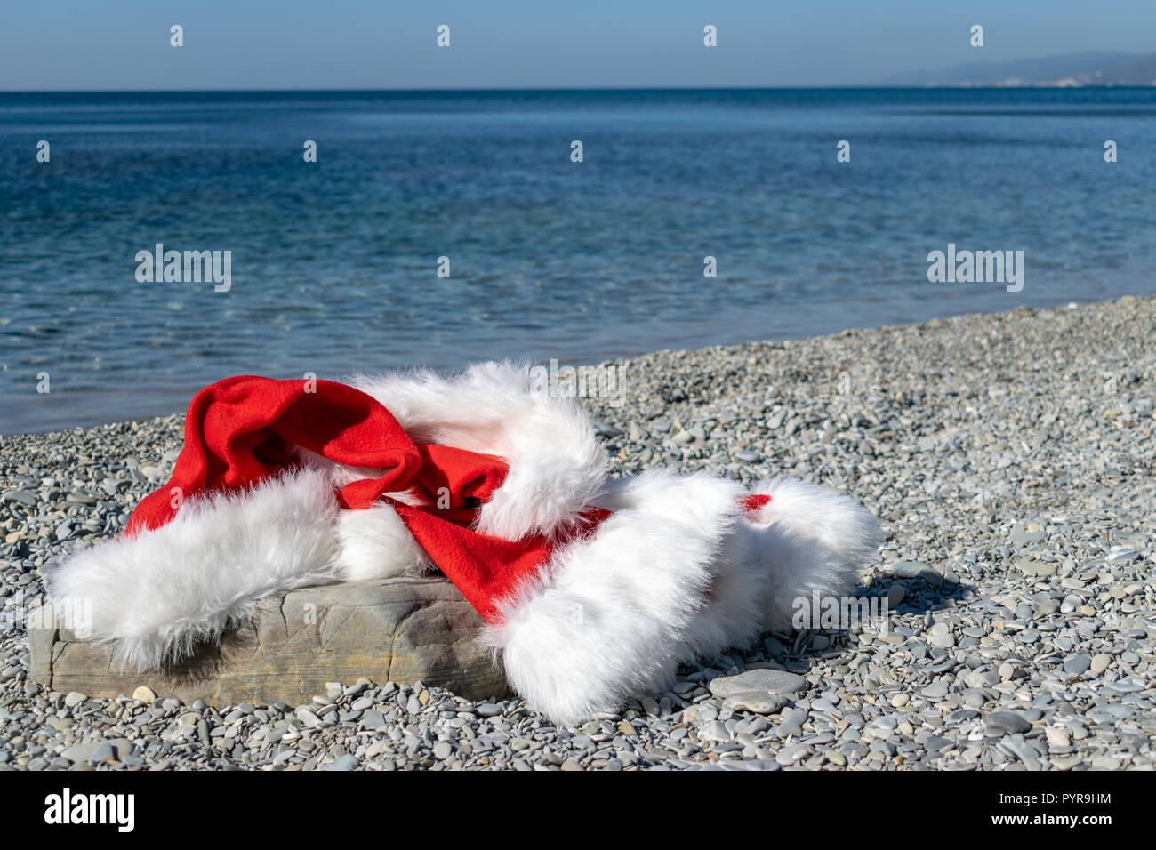 Santa Claus clothing and hat lies on a large stone on the seashore ...