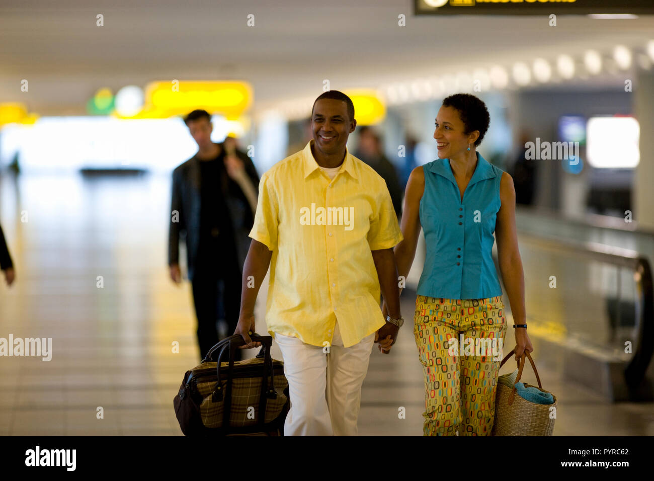 Happy mid-adult couple walking through an airport terminal Stock Photo ...