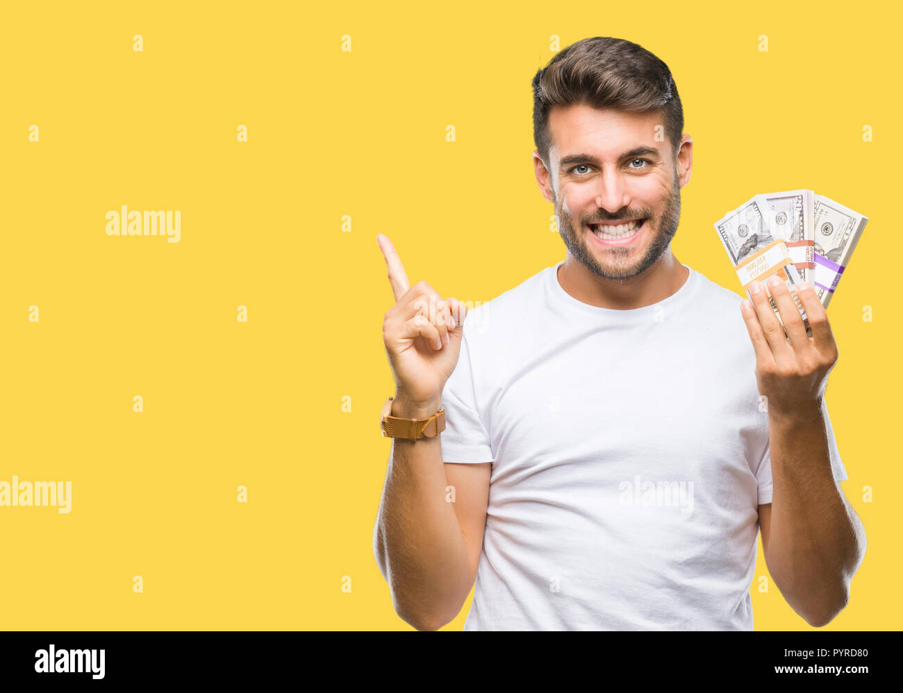 Young handsome man holding stack of dollars over isolated background ...