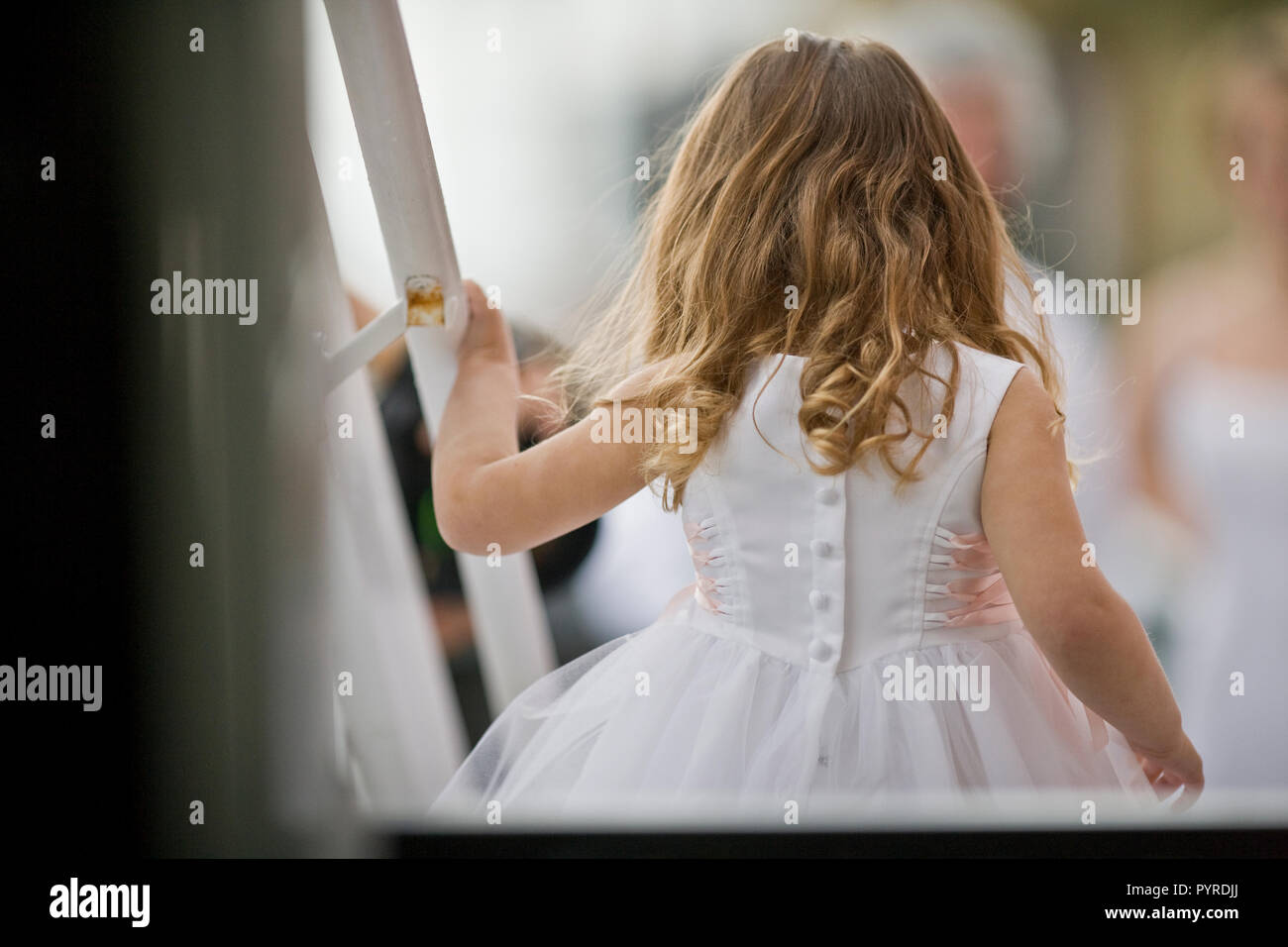 Young girl with long hair dressed as a flowergirl. Stock Photo