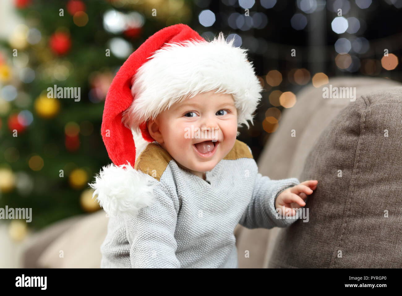 Joyful baby looking at camera in christmas on a couch in the living room at home Stock Photo