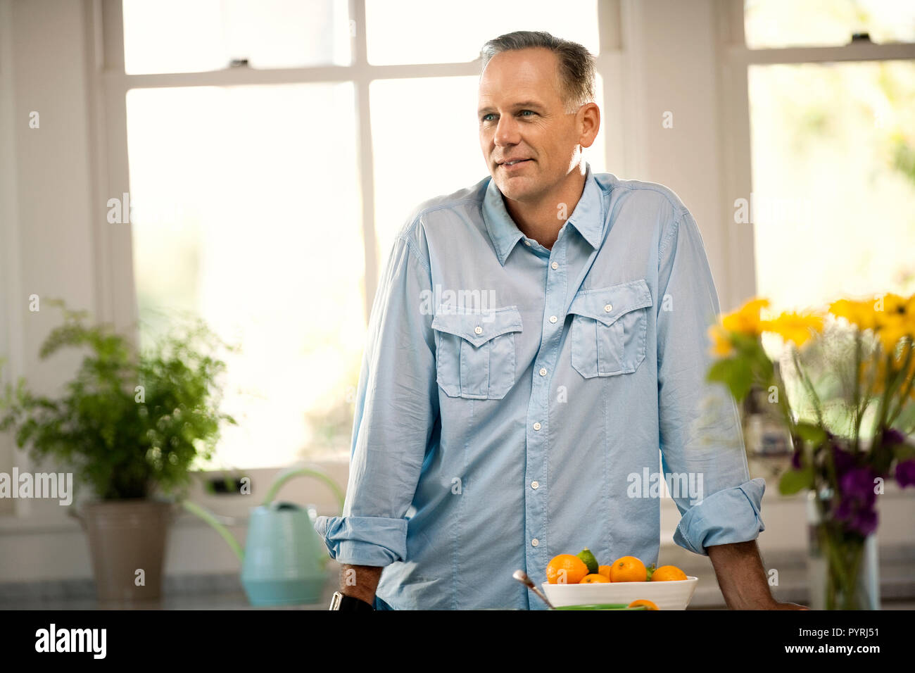Man standing in a light and airy kitchen. Stock Photo