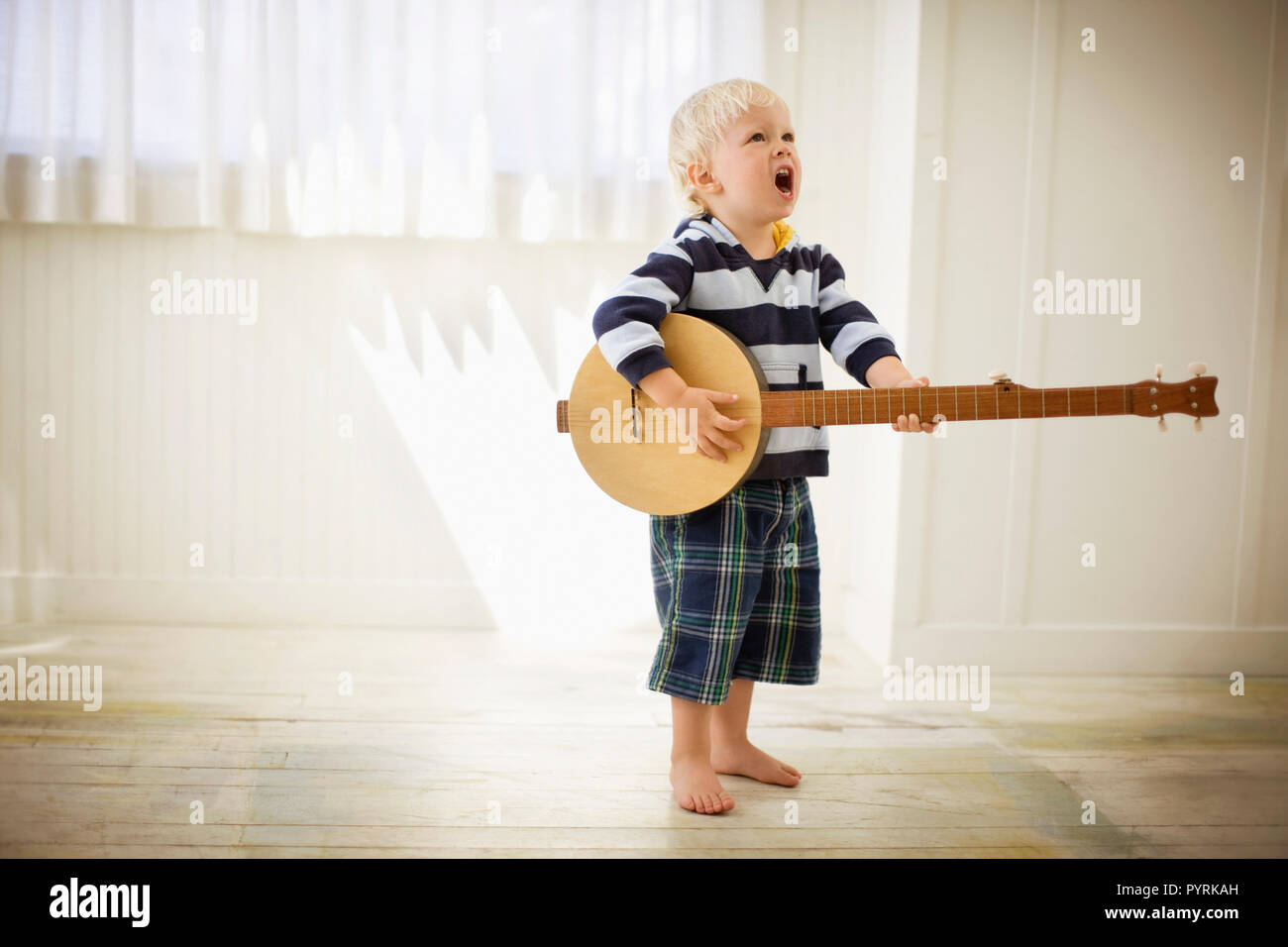 Toddler playing with a wooden banjo. Stock Photo