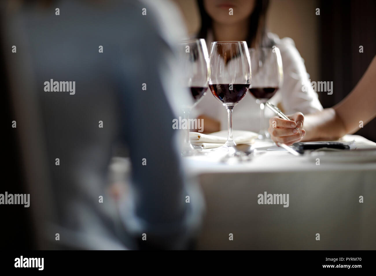 Three colleagues brainstorming while sitting around a table with three wine glasses. Stock Photo