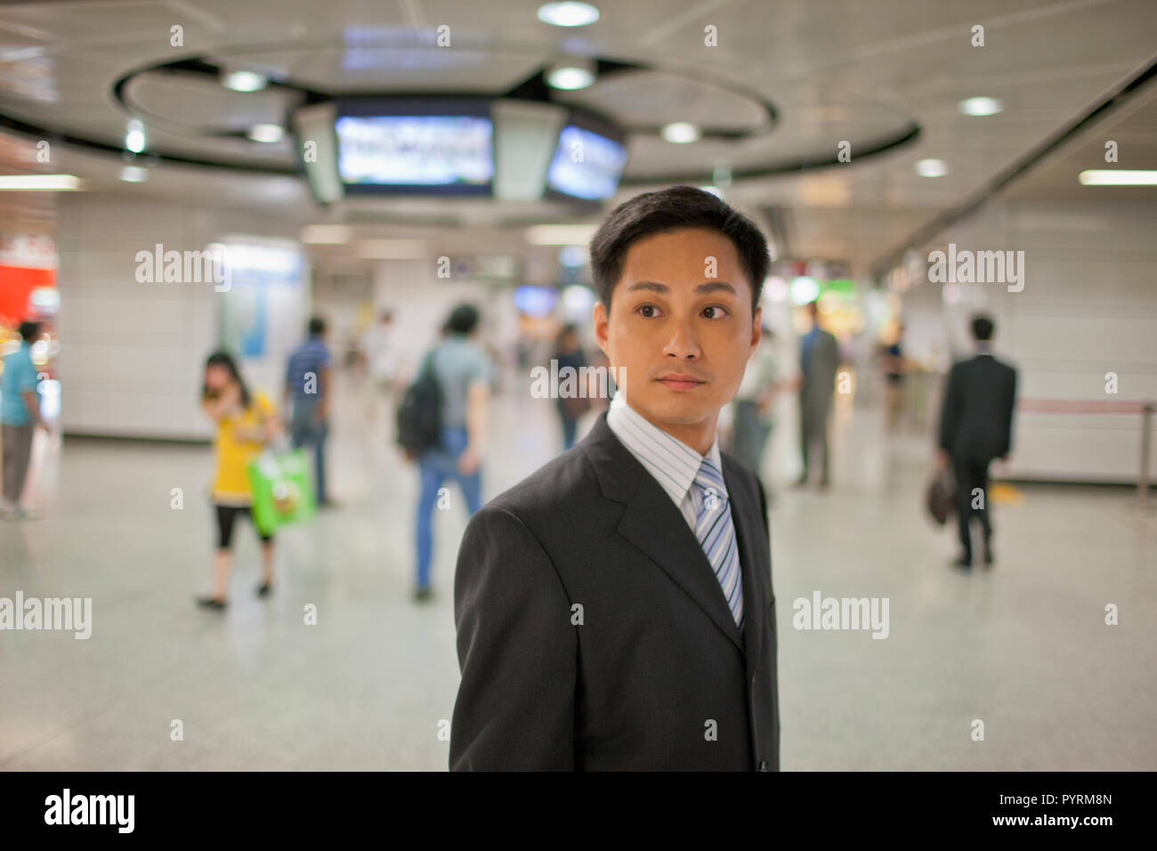 Young businessman standing in a busy train station. Stock Photo