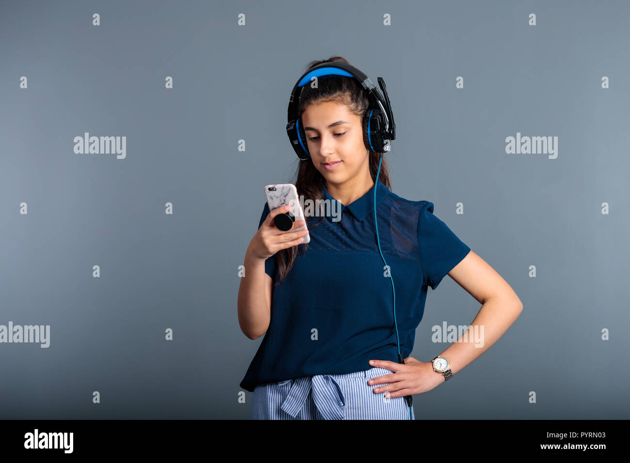 Teenage girl with headphones on while looking on her mobile phone Stock Photo