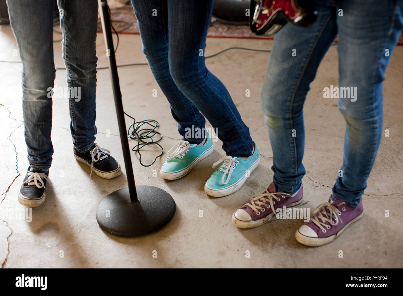 Group of teenage girls standing round a microphone at band practise. Stock Photo