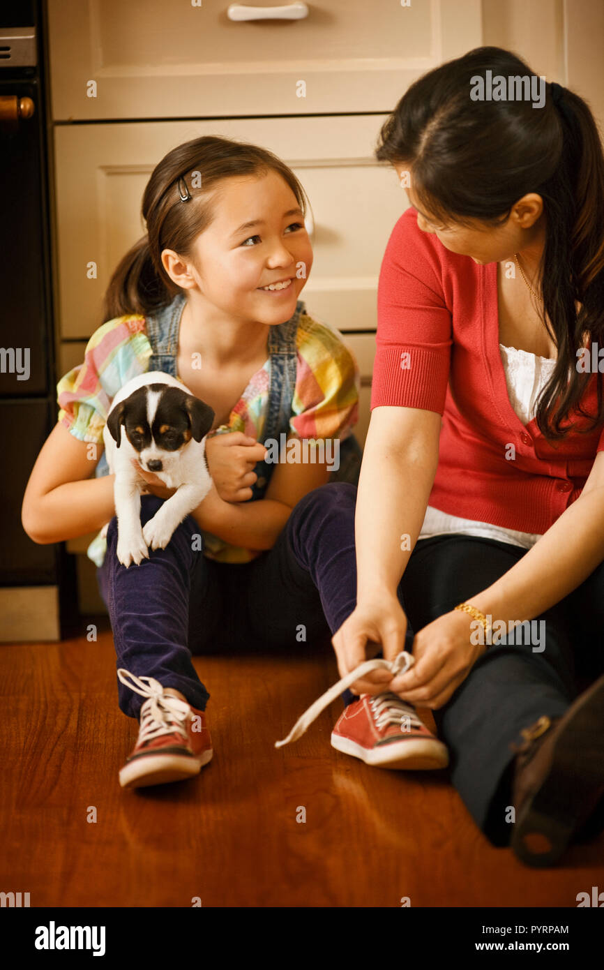 Mother helping her daughter tie her shoelaces. Stock Photo