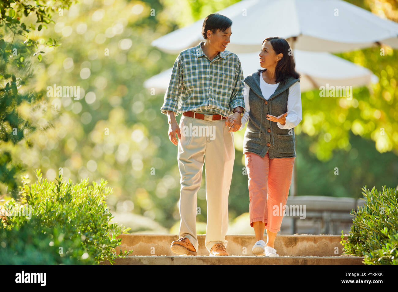 Happy mid adult couple walking hand in hand Stock Photo - Alamy