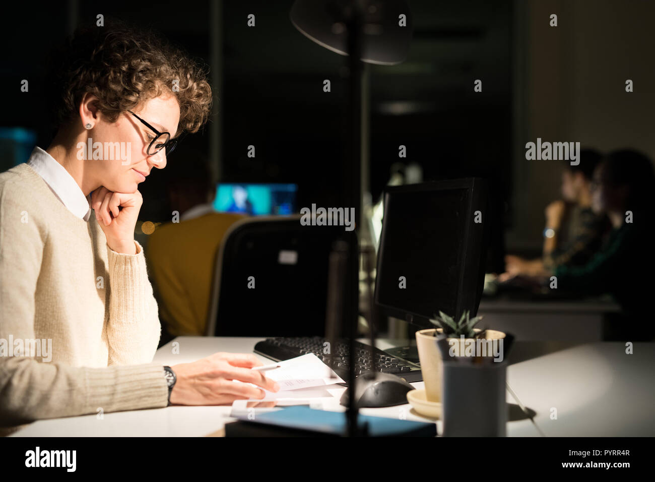 Woman Working in Dark Office Stock Photo