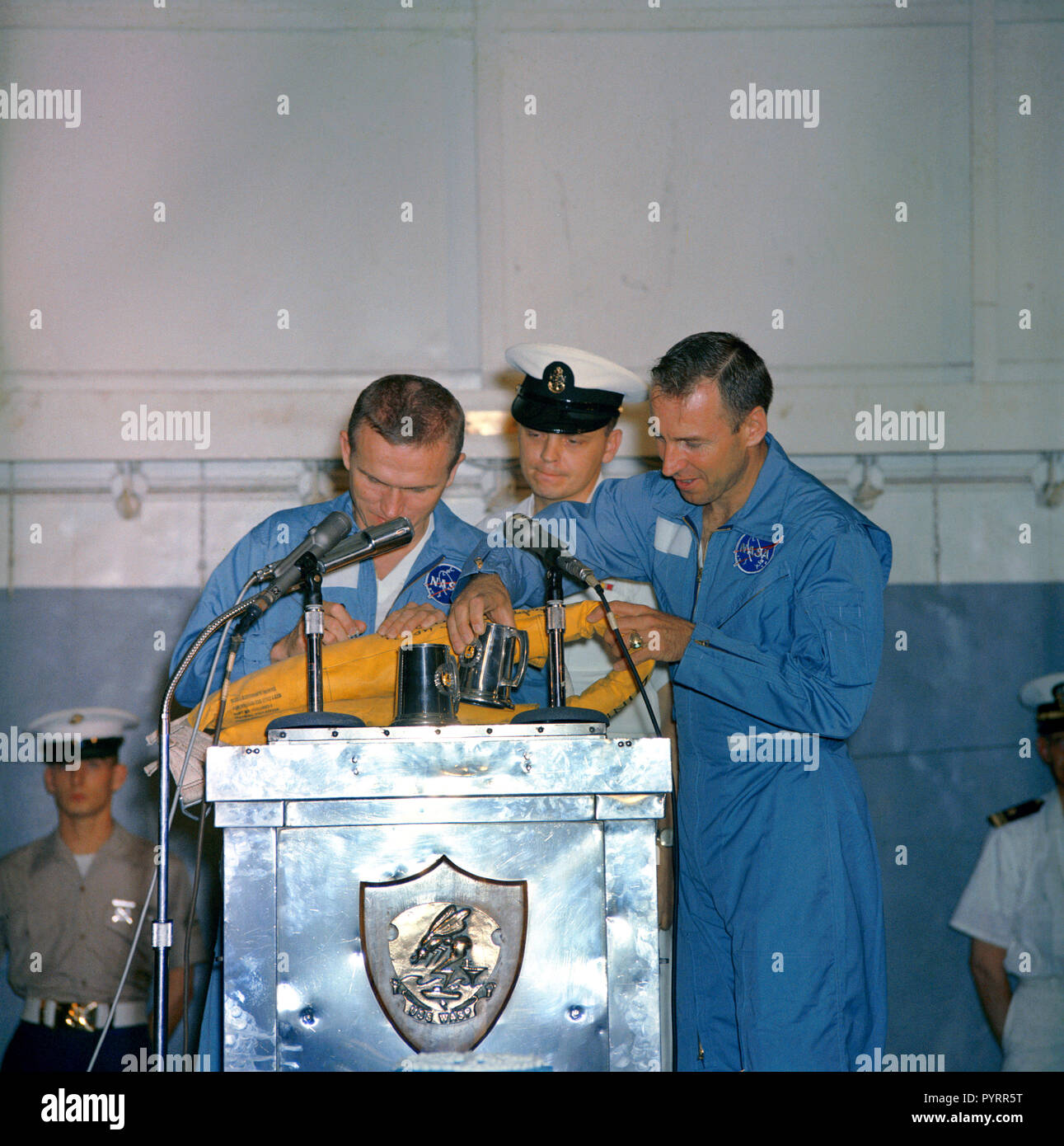 (18 Dec. 1965) --- Astronauts Frank Borman (left), Gemini-7 command pilot, and James A. Lovell Jr., pilot, take time out during their welcoming ceremonies aboard the aircraft carrier USS Wasp to autograph a life preserver. Stock Photo