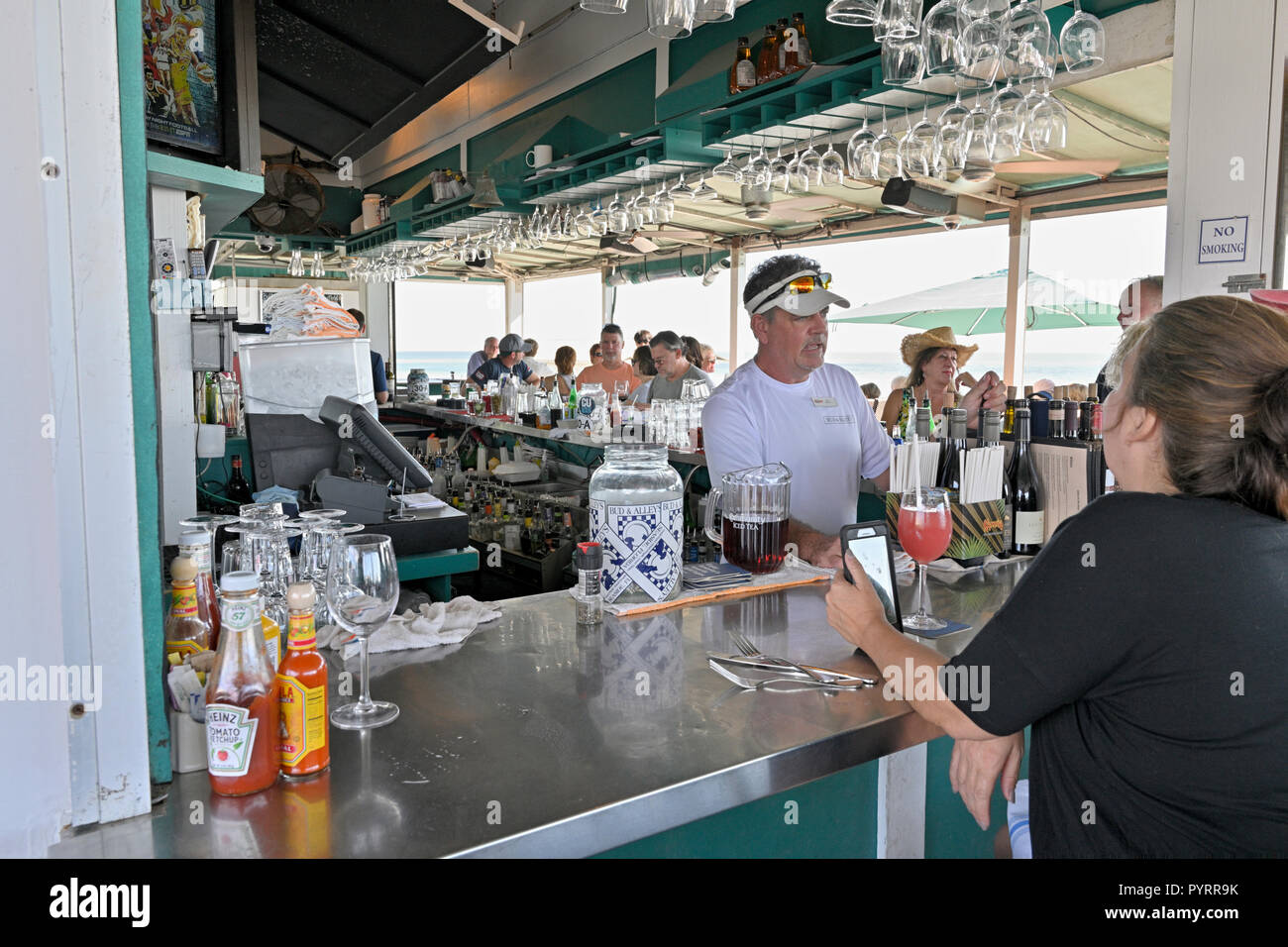 Male bartender behind the bar at the busy rooftop bar and restaurant or grill of Bud and Alley's in the Florida panhandle beach town of Seaside, USA. Stock Photo