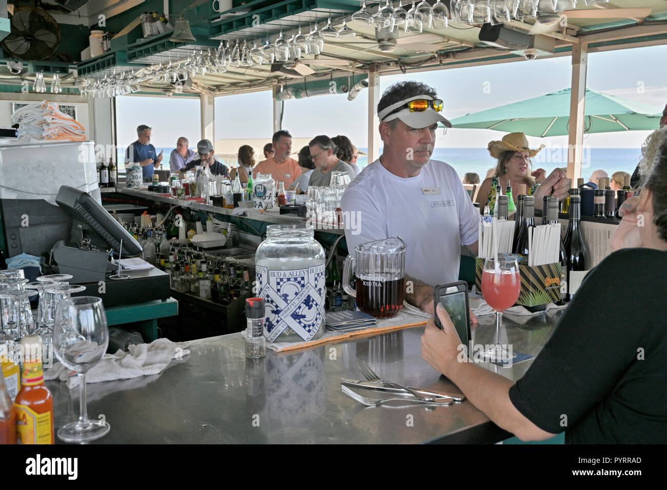 Male bartender behind the bar at the busy rooftop bar and restaurant or grill of Bud and Alley's in the Florida panhandle beach town of Seaside, USA. Stock Photo