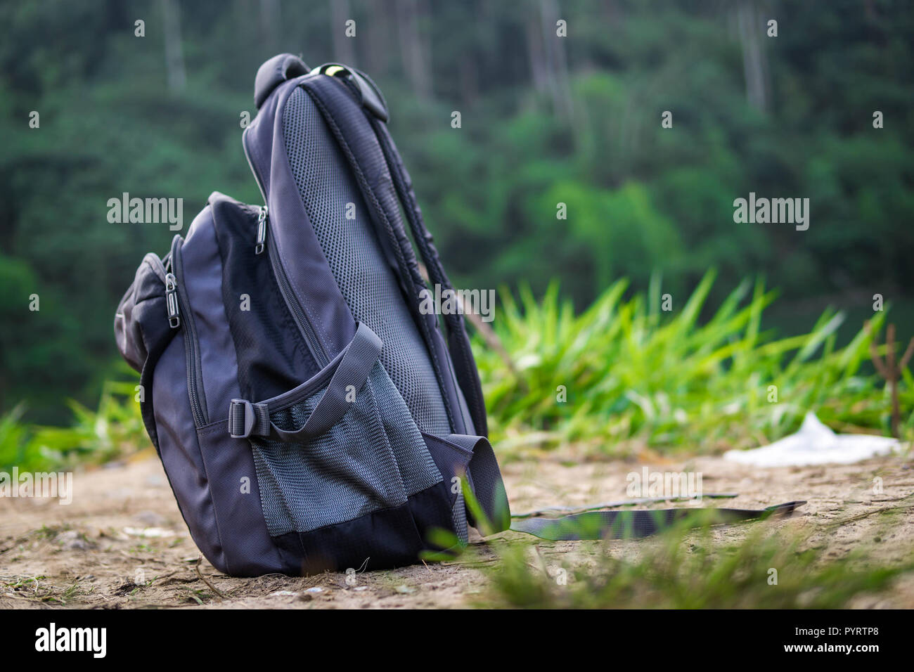 A rucksack on a ground with a blurry nature background. Stock Photo