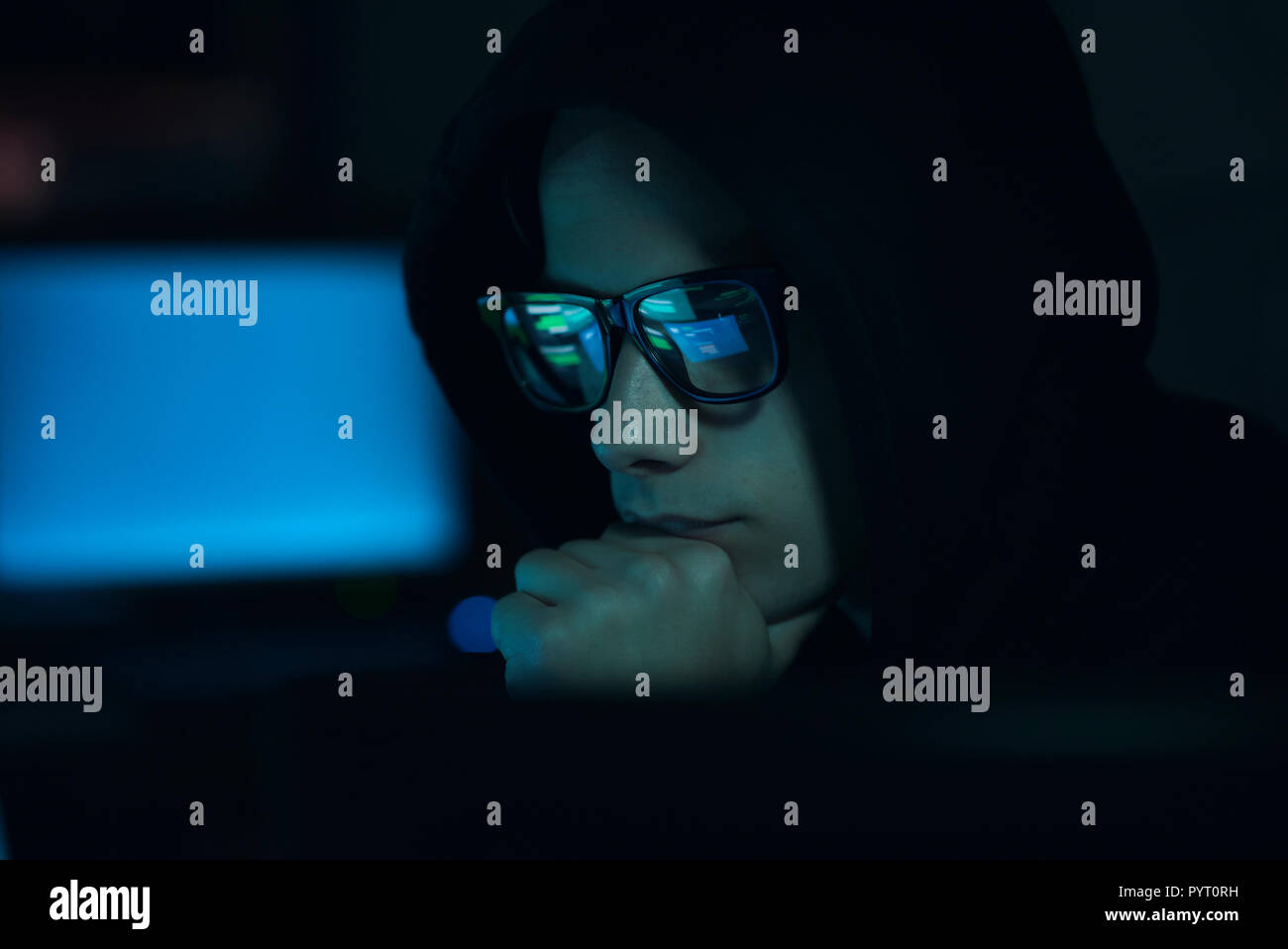 Young professional hacker working in a dark office with computers ...