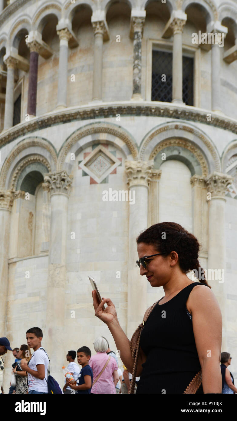 A woman using her mobile phone by the leaning tower of Pisa. Stock Photo