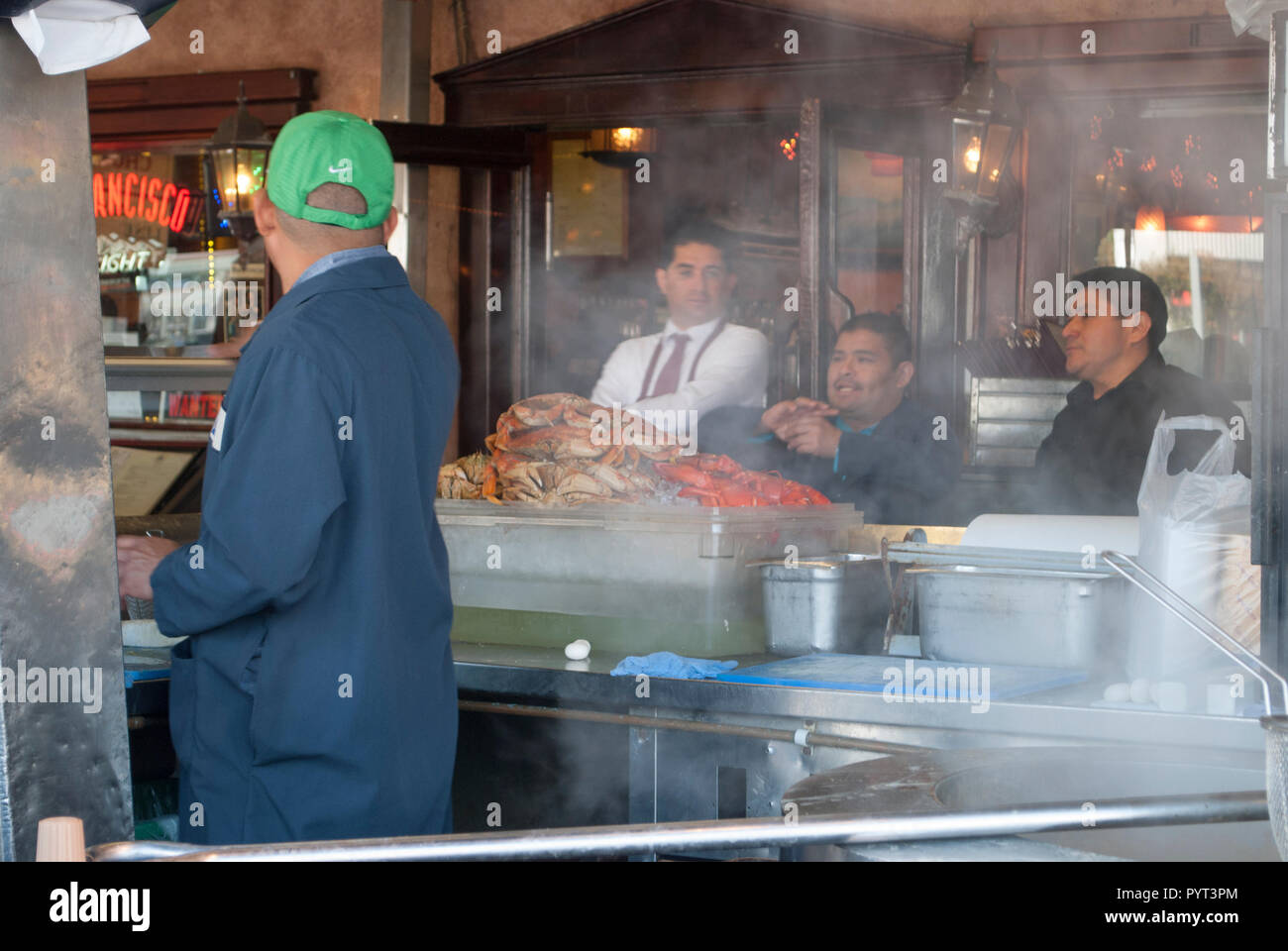 Scene at street restaurant with cook preparing fresh crabs, waiter and visitors close up Stock Photo