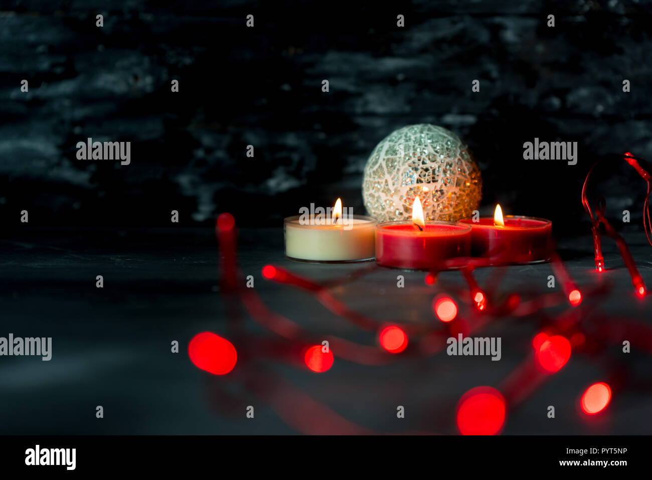 christmas candles and red lights on dark, rustic background Stock Photo
