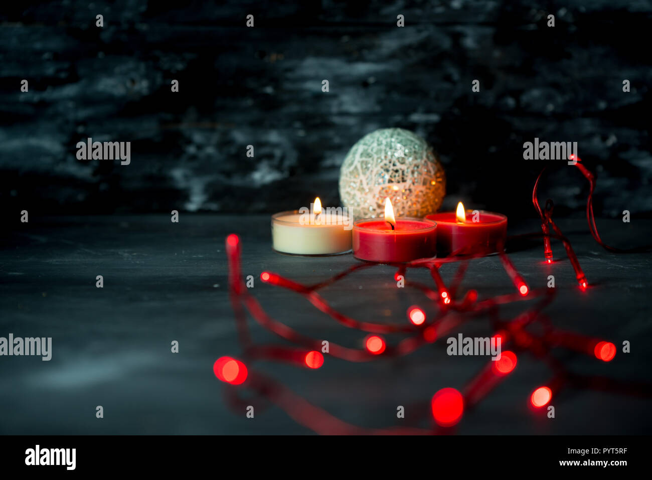 christmas candles and red lights on dark, rustic background Stock Photo