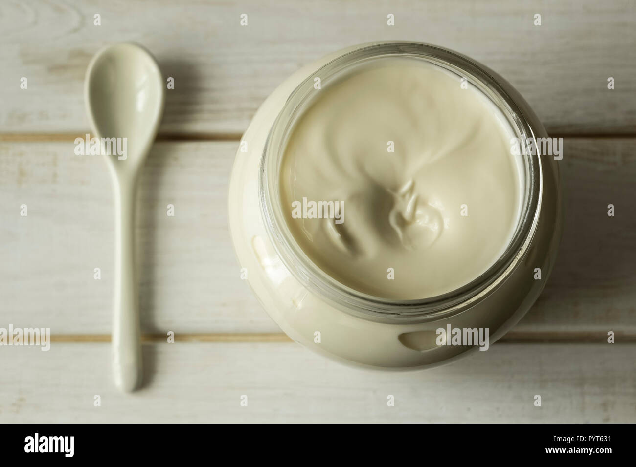 Mayonnaise in a glass jar with a spoon on white wooden boards. Stock Photo
