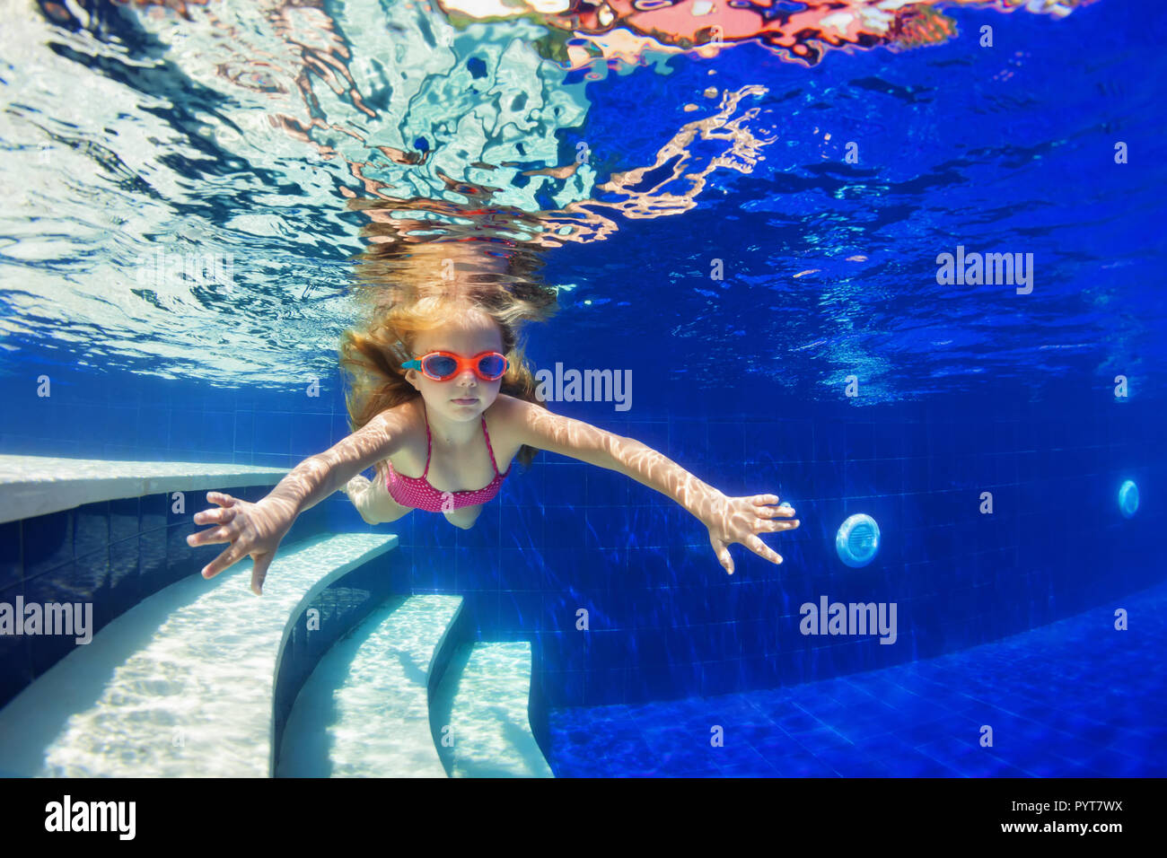 Happy family in swimming pool. Smiling child in goggles swim, dive in pool with fun - jump deep down underwater. Healthy lifestyle, people water sport Stock Photo