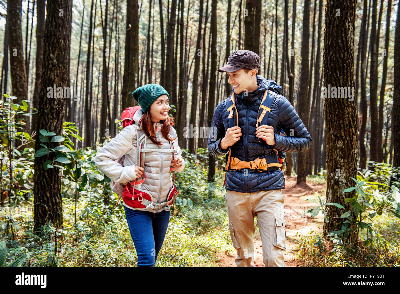 Young asian couple hikers with backpack walking on forest path Stock ...