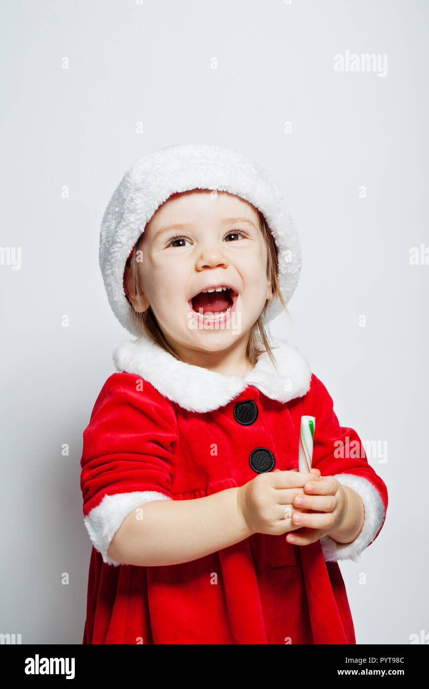 Cute child girl in Santa hat having fun and laughing on white
