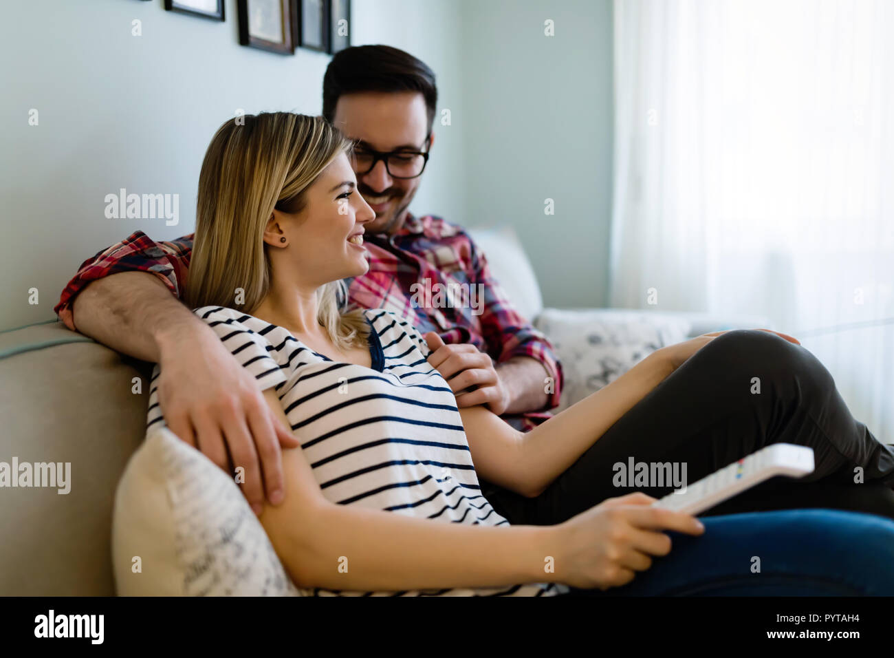 Happy couple watching tv in their house Stock Photo
