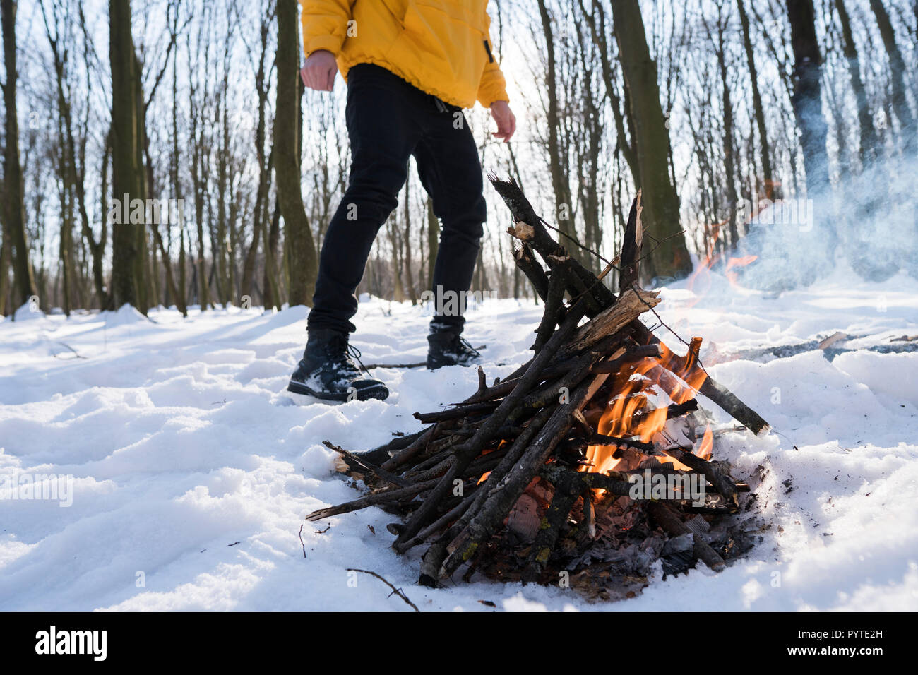 Young man in yellow jacket in the winter forest standing near small