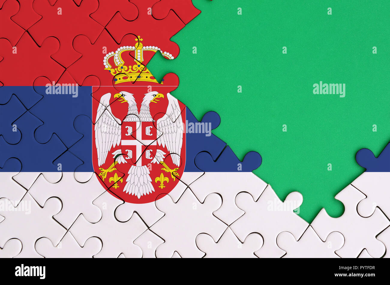 Serbia flag is depicted on a completed jigsaw puzzle with free green ...