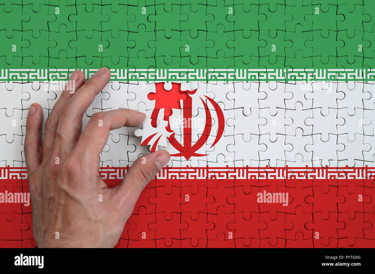 Iran flag is depicted on a puzzle, which the man's hand completes to fold  Stock Photo - Alamy
