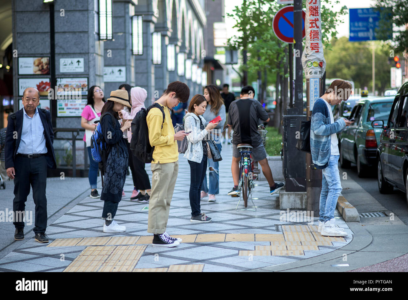 People in the streets of Kyoto, looking at their mobile phones Stock Photo