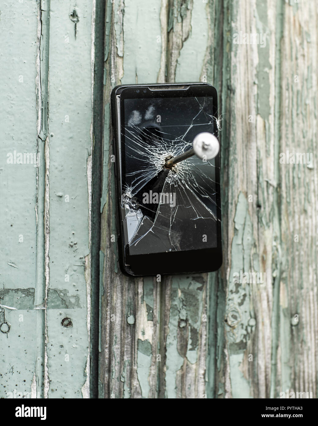 concept of obsolete technology:mobile phone nailed to the fence a large nail Stock Photo