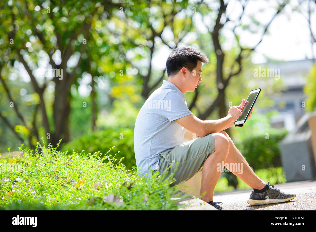 Young asian man using tablet in park Stock Photo