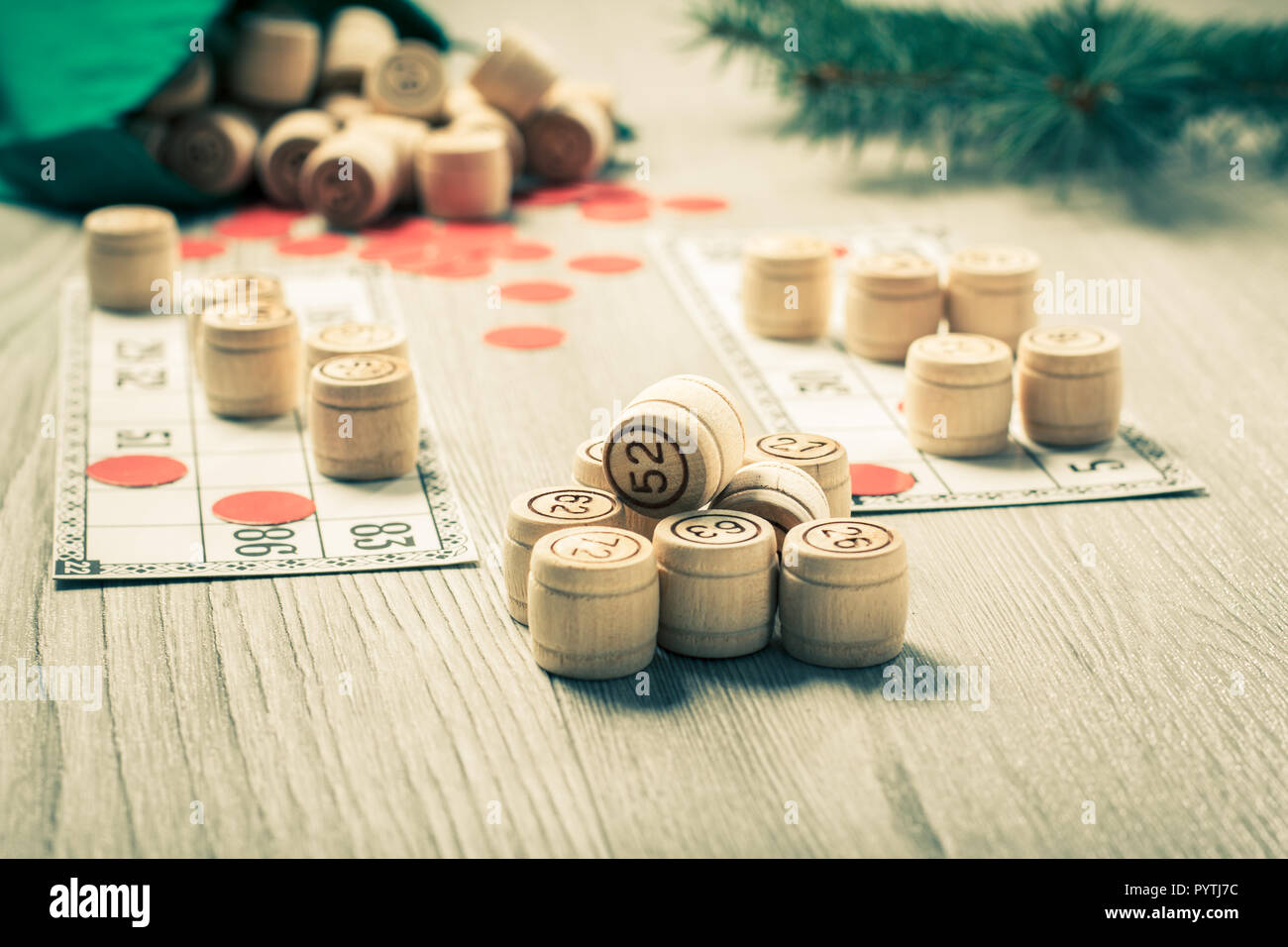 Board game lotto. Wooden lotto barrels with green bag, game cards and Christmas fir tree branches. Color toning effect. Stock Photo