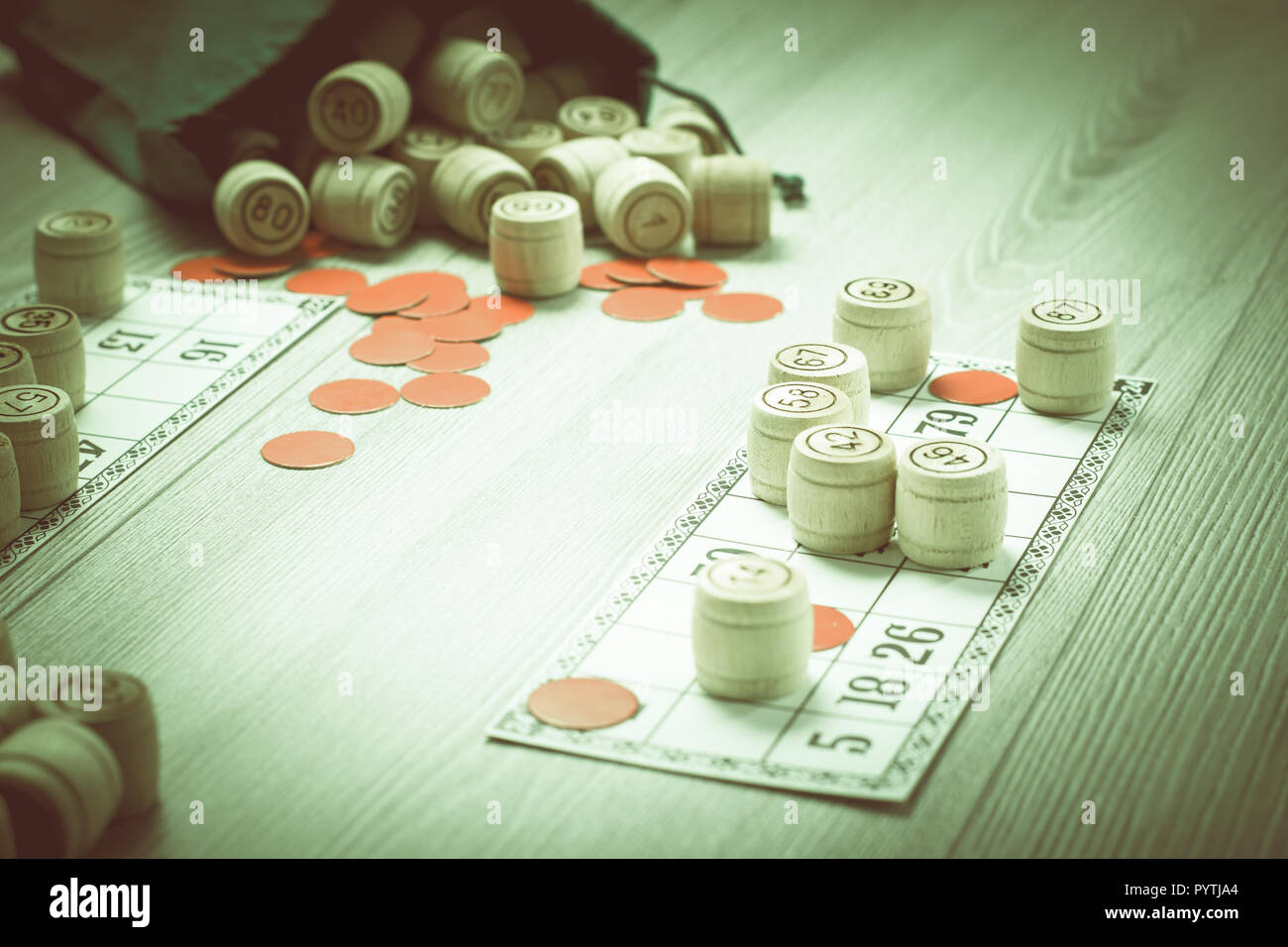 Board game lotto. Wooden lotto barrels with bag, game cards and red chips for a game in lotto. Shallow depth of field. Color toning effect. Stock Photo