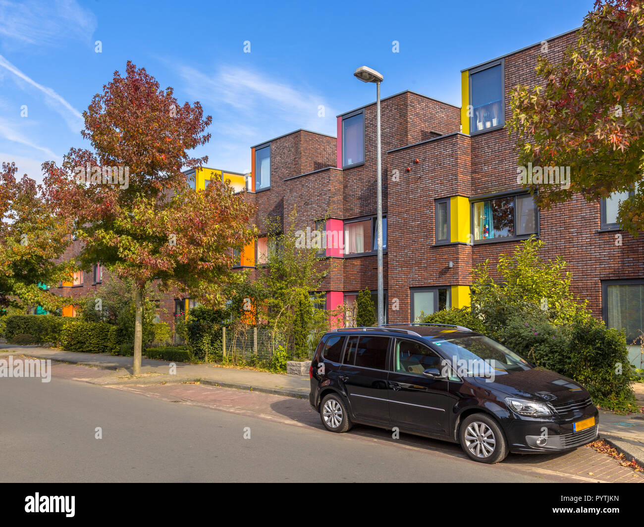Colorful modern suburban family row houses in a lively proper neighborhood with trees and gardens Stock Photo