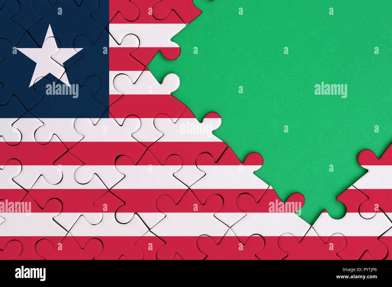 Liberia flag  is depicted on a completed jigsaw puzzle with free green copy space on the right side. Stock Photo
