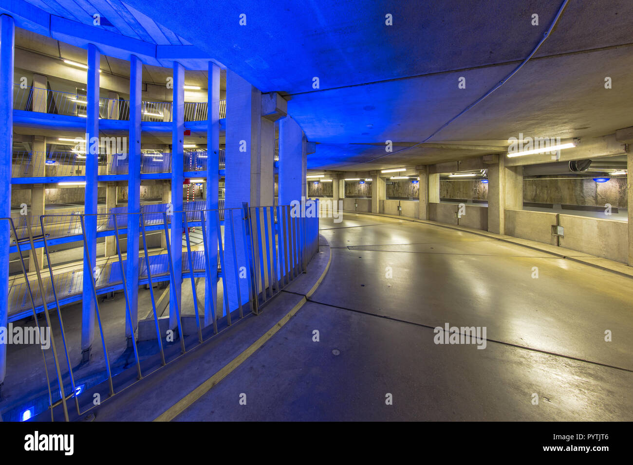 Empty ramp in circular underground parking garage with colorful lighting under an international airport Stock Photo