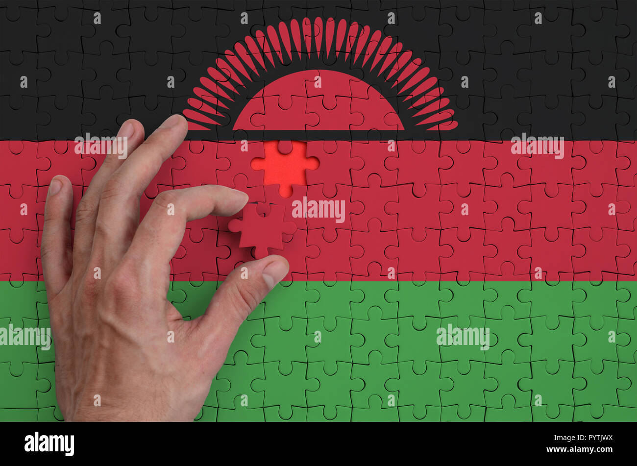 Malawi flag is depicted on a puzzle, which the man's hand completes to ...