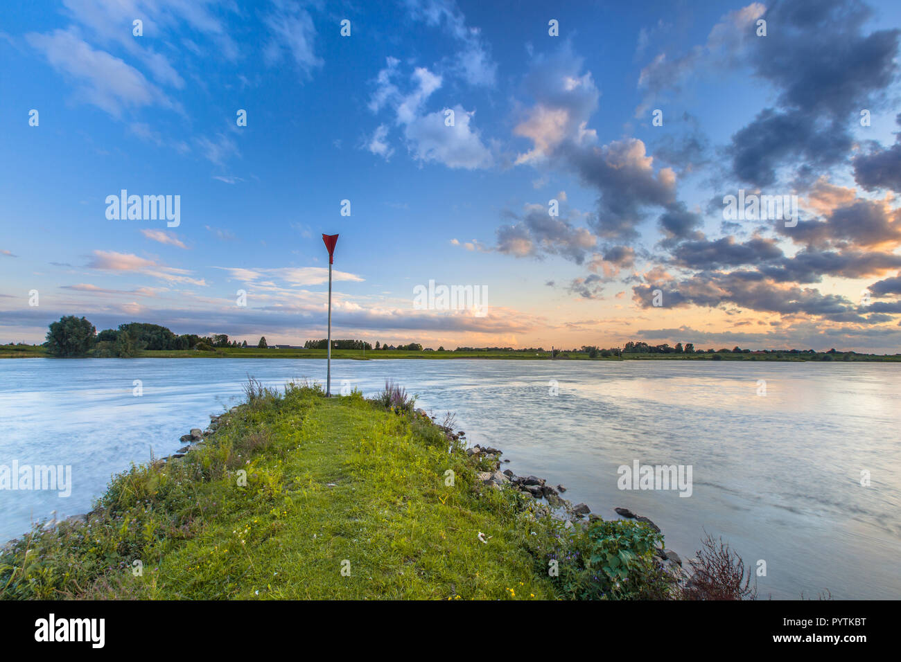 Pier in the river Rhine with bright blue skay and beautiful cloudscape during sunset Stock Photo