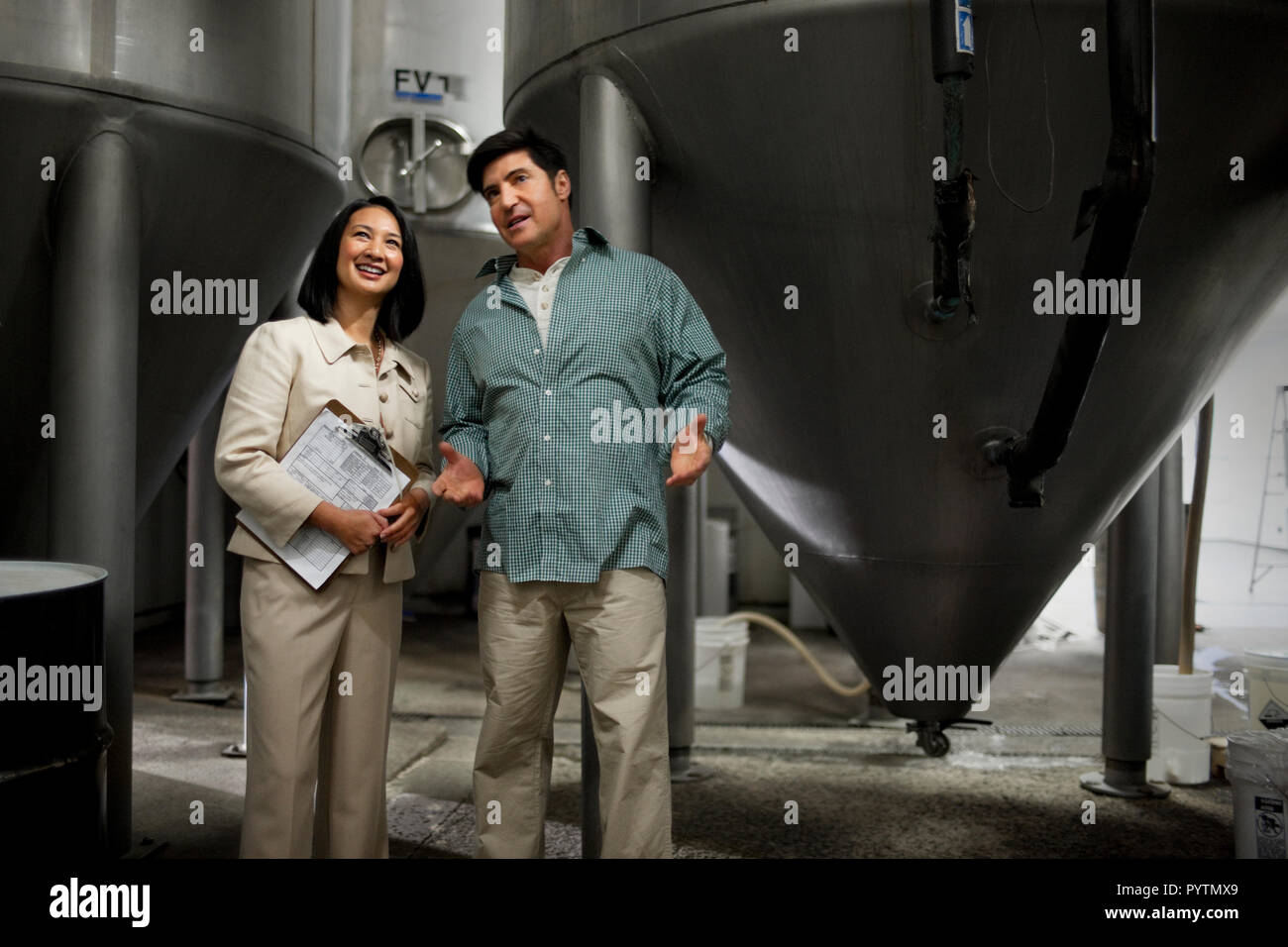 Two smiling colleagues discussing work in a warehouse. Stock Photo