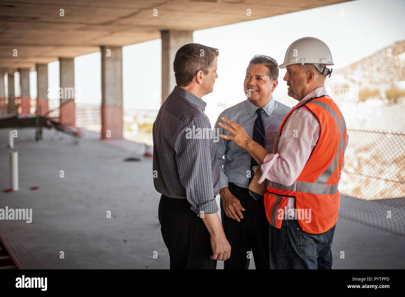 A construction manager and two executives talking on construction site. Stock Photo