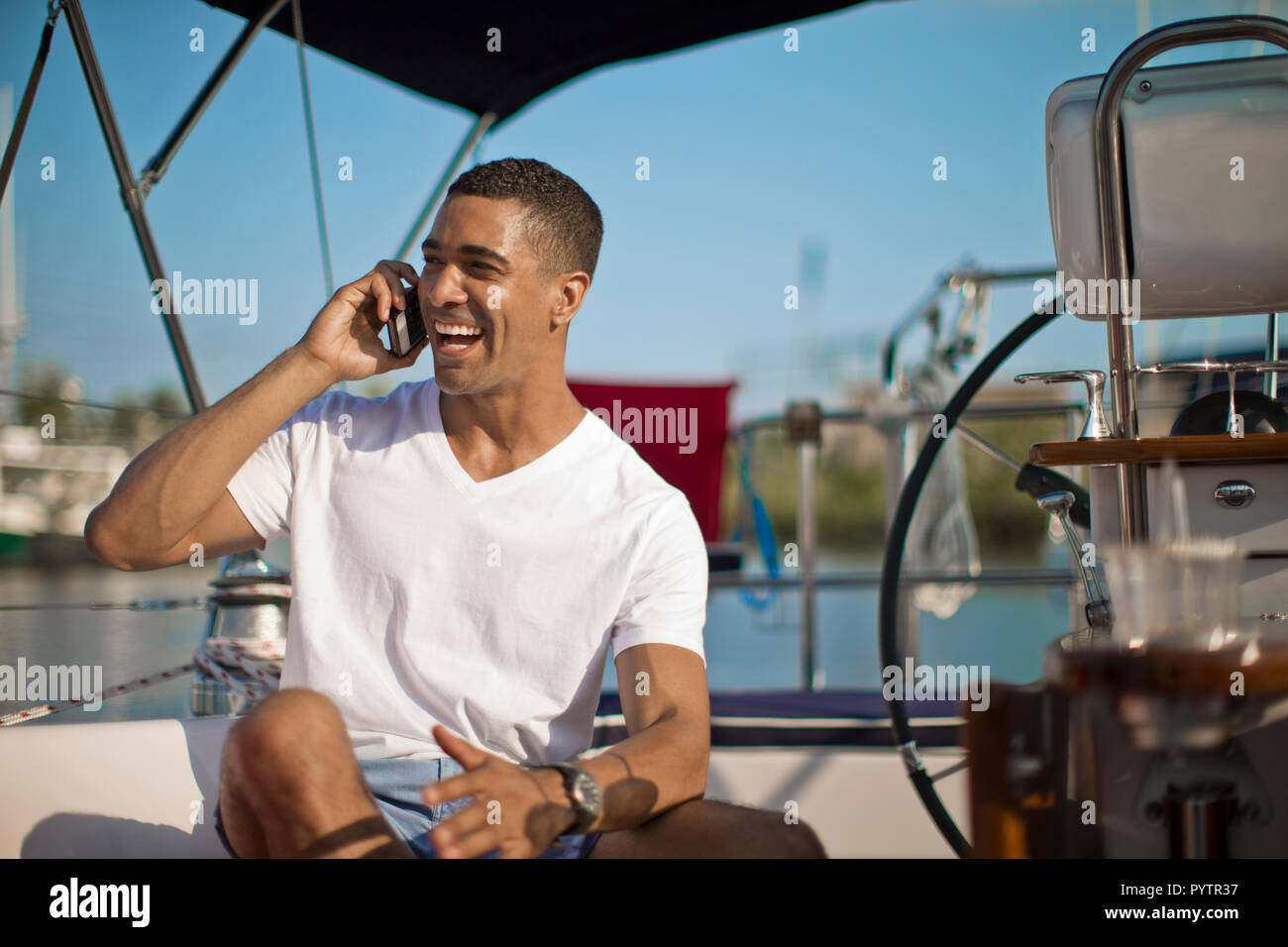 Smiling young man talking on his cell phone on a boat. Stock Photo