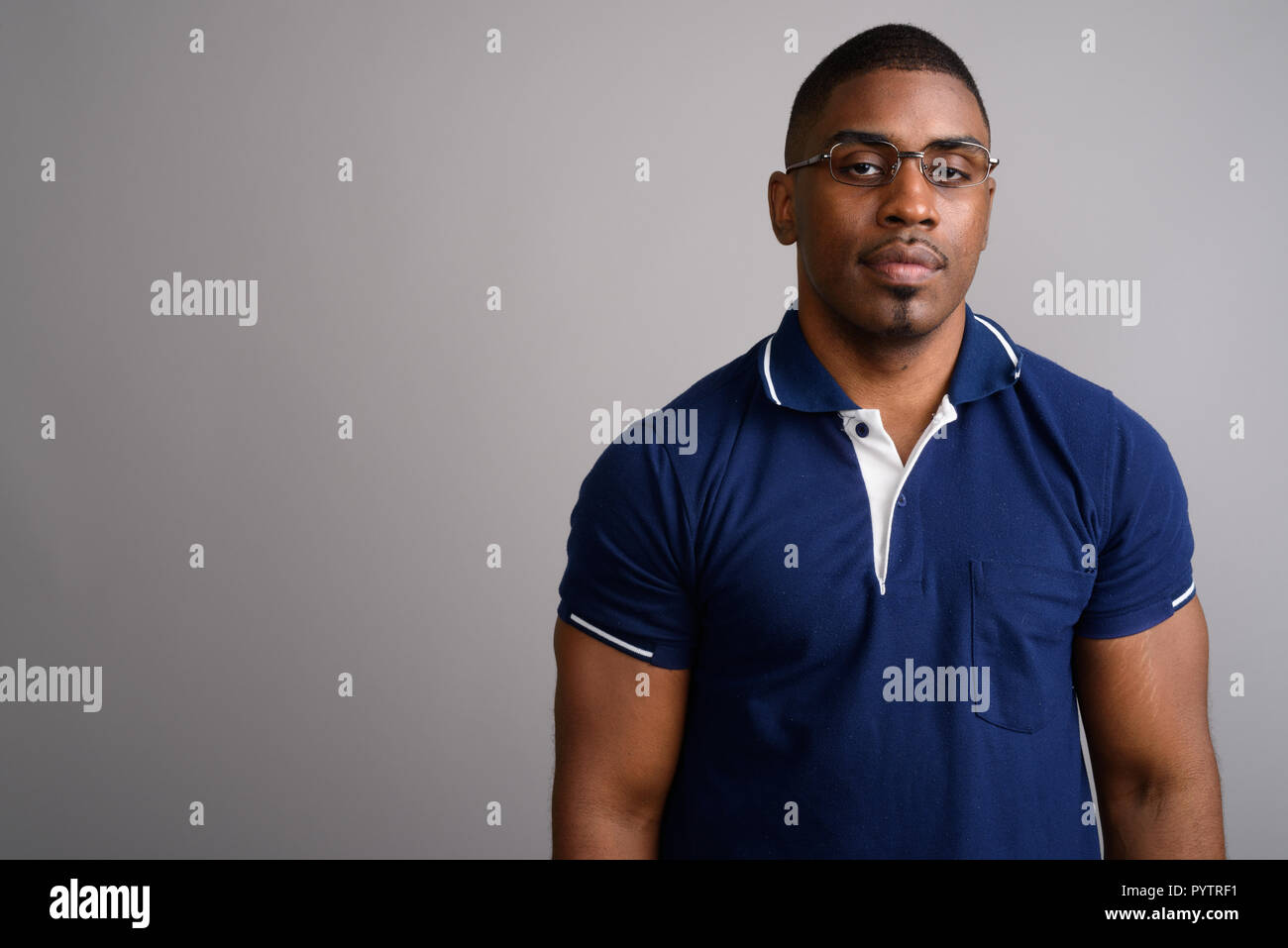 Young handsome African man wearing blue polo shirt against gray  Stock Photo