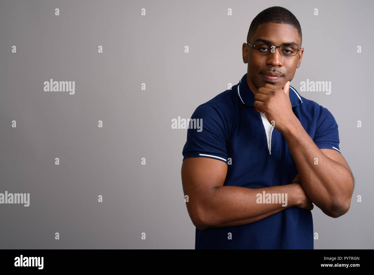 Young handsome African man wearing blue polo shirt against gray  Stock Photo