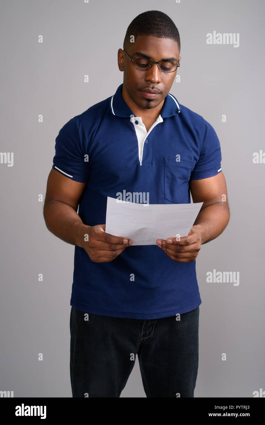 Young handsome African man wearing blue polo shirt against gray  Stock Photo