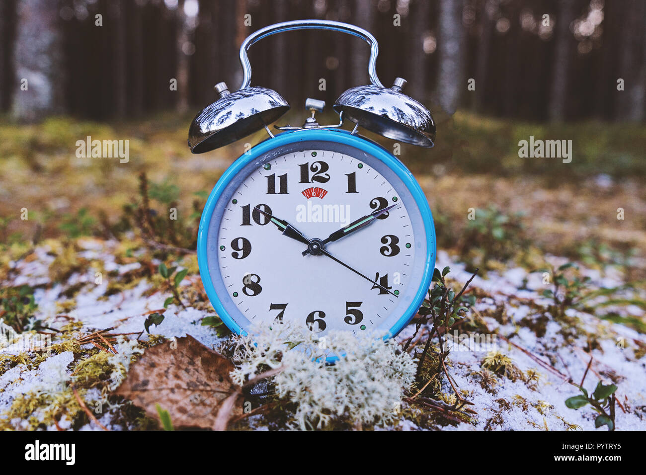 Concept of transition to winter time. Vintage blue alarm clock on